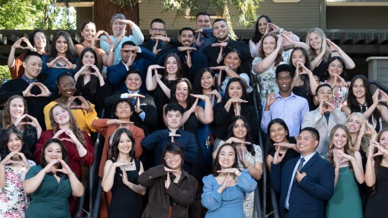 Photos shows the students, facutly and staff of OT Pinning Ceremony. They are all forming either the letter O or the letter T with their hands.
