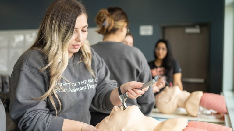 Image shows a PA student practicing a procedure on a mannequin.