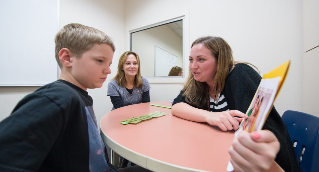 a child works with a speech-language pathologist student in a clinical setting